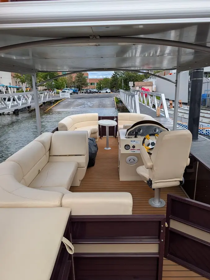 Shaded lower deck of the pontoon boat with wraparound seating and helm
